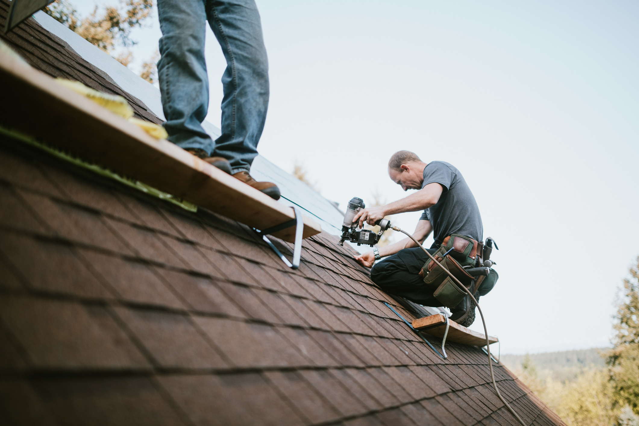 A roofer and crew work on putting in new roofing shingles. Small local business serving local families